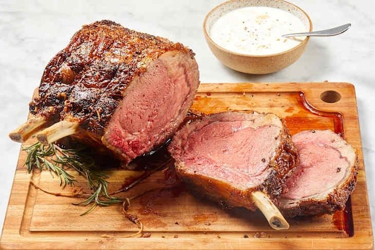 Skivat, rosa kött på skärbräda med rosmarin och sås