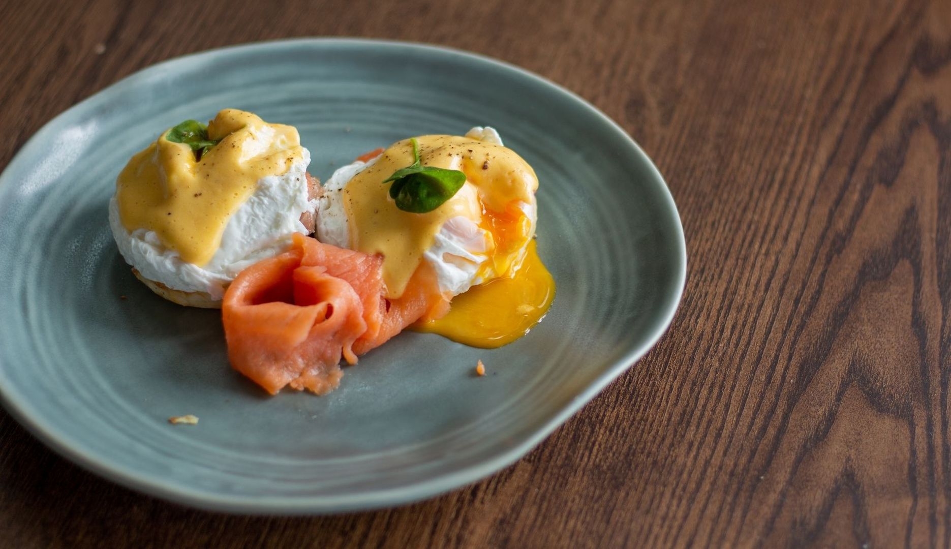 Pocherade ägg med hollandaise, lax och rinnande äggula på en tallrik